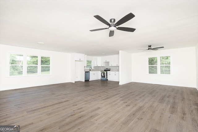 unfurnished living room with wood finished floors, ceiling fan, and a sink