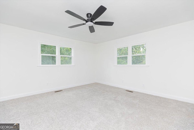 carpeted spare room with a ceiling fan, plenty of natural light, and baseboards