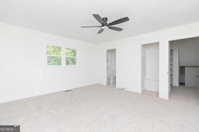 unfurnished bedroom with carpet floors, baseboards, ensuite bath, and ceiling fan