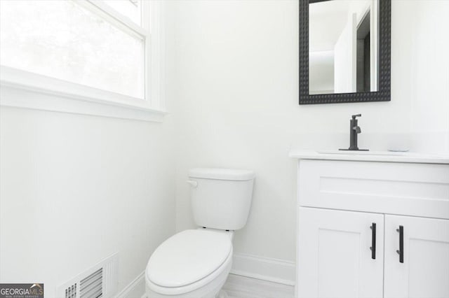 bathroom featuring baseboards, vanity, and toilet