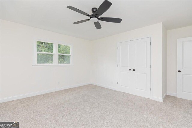 unfurnished bedroom featuring carpet floors, baseboards, a closet, and a ceiling fan