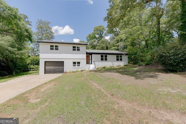 tri-level home featuring an attached garage, concrete driveway, and a front yard