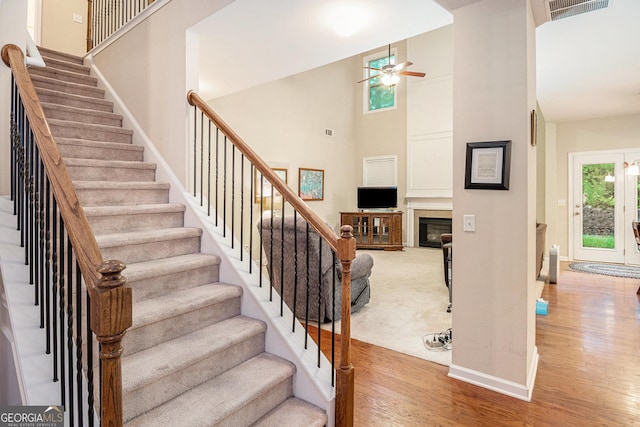 4889 Arbor View Pkwy NW, Acworth, GA 30101 - staircase featuring ceiling fan, wood finished floors, a high ceiling, and a glass covered fireplace