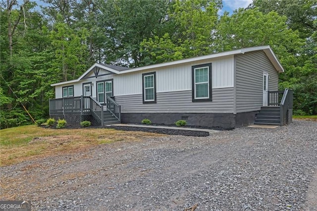 manufactured / mobile home with crawl space, gravel driveway, and a deck