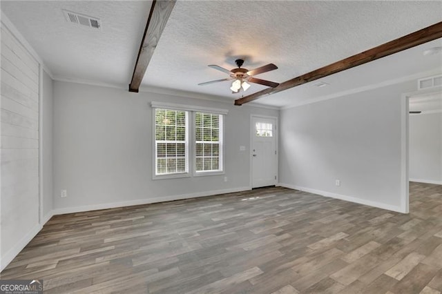 unfurnished room featuring a textured ceiling, beam ceiling, ceiling fan, wood finished floors, and baseboards