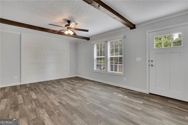 entrance foyer featuring a textured ceiling, a ceiling fan, beam ceiling, wood finished floors, and baseboards