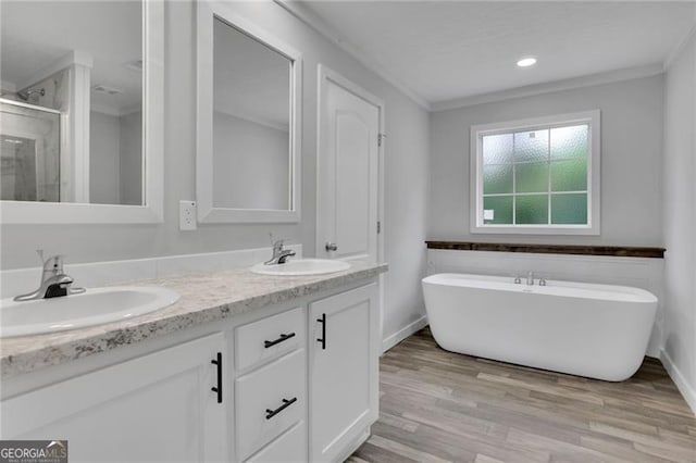 full bath with ornamental molding, a shower stall, double vanity, wood finished floors, and a soaking tub