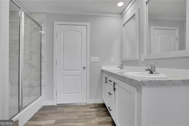 bathroom featuring a stall shower, wood finished floors, double vanity, recessed lighting, and baseboards