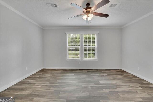 empty room with ceiling fan, wood finished floors, ornamental molding, a textured ceiling, and baseboards