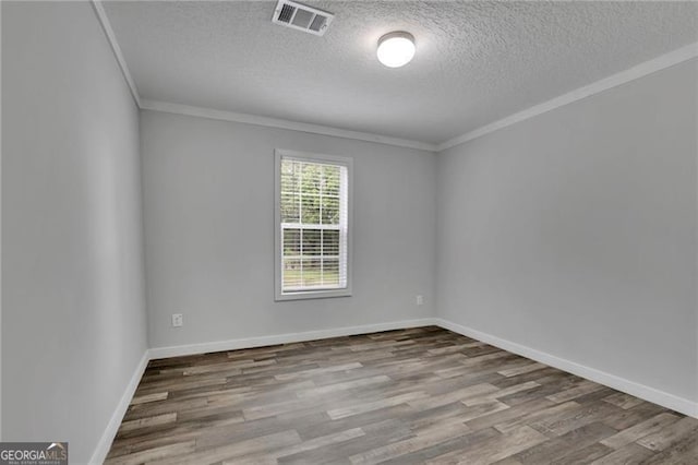 spare room with wood finished floors, crown molding, a textured ceiling, and baseboards