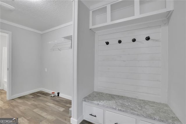 mudroom featuring a textured ceiling, light wood-style floors, baseboards, and crown molding