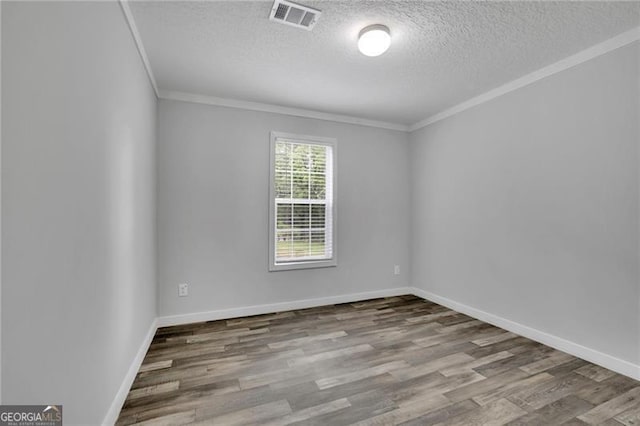 empty room with ornamental molding, wood finished floors, a textured ceiling, and baseboards
