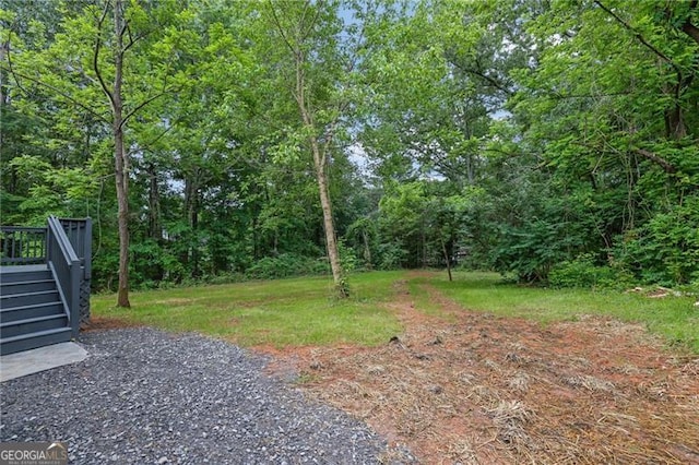 view of yard featuring stairway, a forest view, and a wooden deck