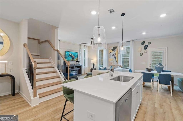 kitchen with a sink, stainless steel dishwasher, open floor plan, light wood finished floors, and recessed lighting
