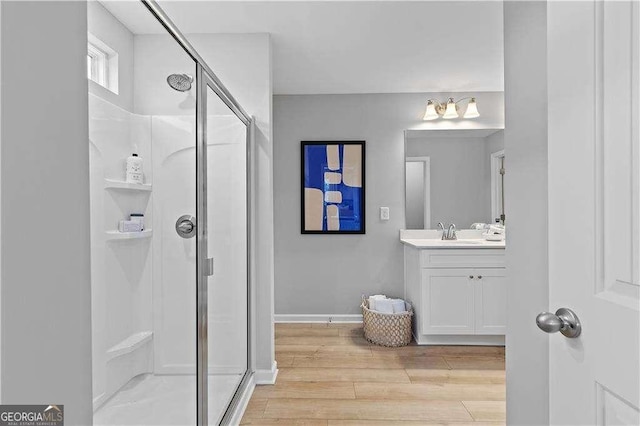 full bathroom featuring a stall shower, wood finished floors, vanity, and baseboards