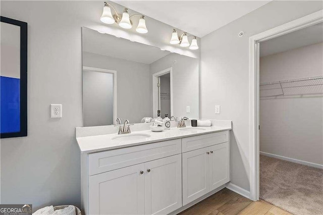bathroom featuring a spacious closet, double vanity, and wood finished floors
