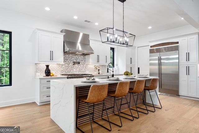 2595 Grassview Dr, Milton, GA 30004 - kitchen with stainless steel appliances, wall chimney exhaust hood, backsplash, a center island with sink, and a sink