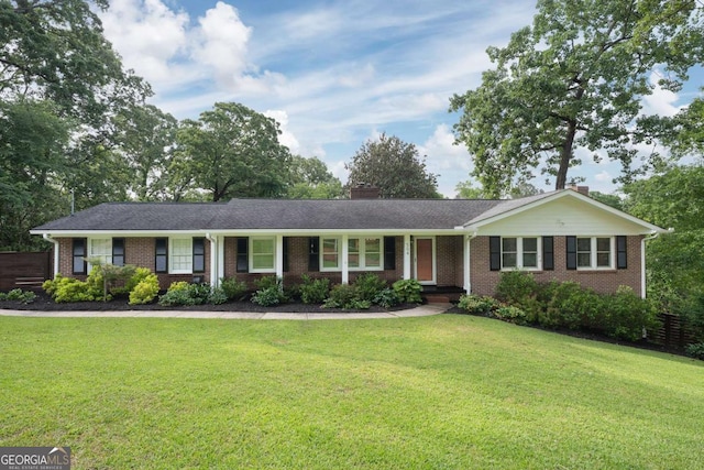 ranch-style home with a chimney, brick siding, and a front yard
