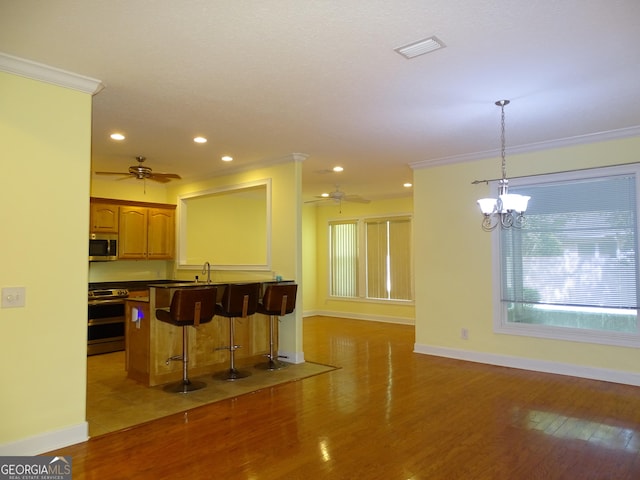228 Laurel Landing Blvd, Kingsland, GA 31548 - kitchen with appliances with stainless steel finishes, a ceiling fan, a breakfast bar, crown molding, and recessed lighting