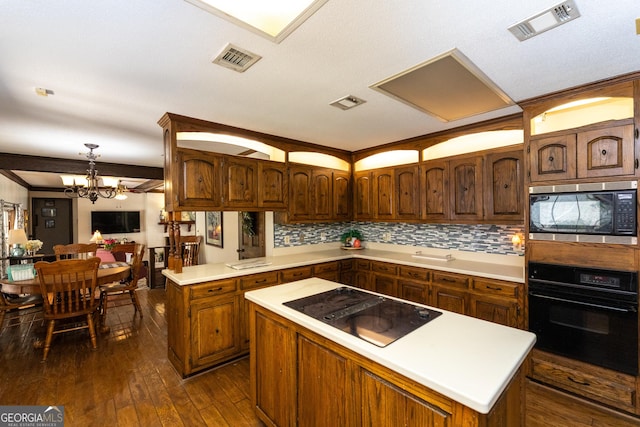 1701 City Blvd, Waycross, GA 31501 - kitchen with black appliances, dark wood finished floors, light countertops, a kitchen island, and a chandelier