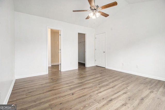unfurnished bedroom with wood finished floors, baseboards, a ceiling fan, high vaulted ceiling, and a closet