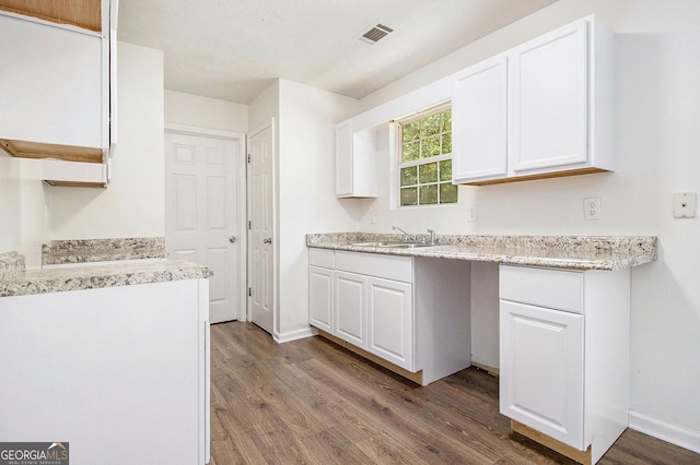 kitchen featuring wood finished floors, a sink, white cabinets, and light countertops