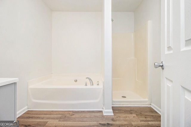 bathroom featuring wood finished floors, a garden tub, and walk in shower