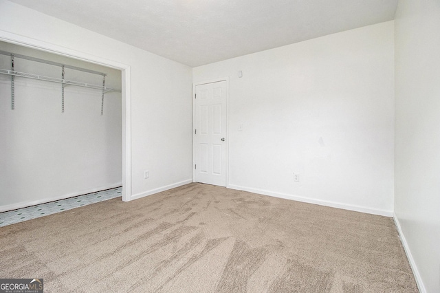 unfurnished bedroom featuring carpet, baseboards, and a closet