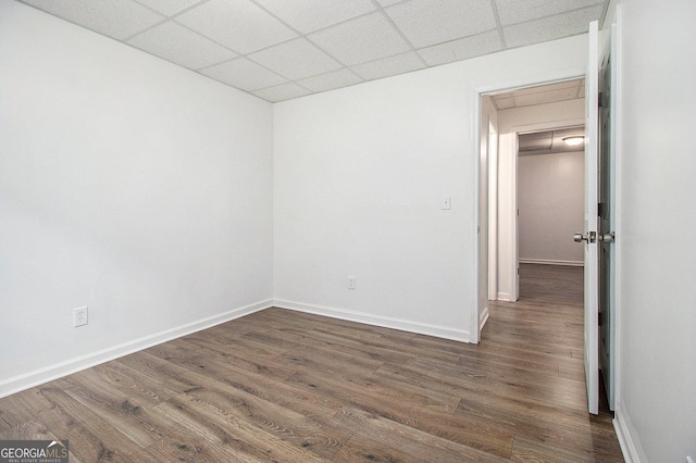 unfurnished room with a drop ceiling, dark wood-type flooring, and baseboards