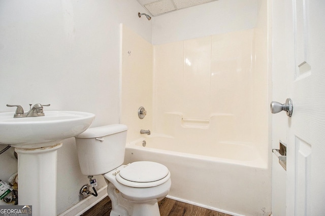 full bath featuring wood finished floors, toilet, tub / shower combination, a sink, and baseboards