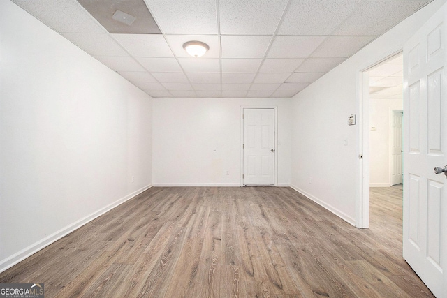spare room featuring wood finished floors, a paneled ceiling, and baseboards
