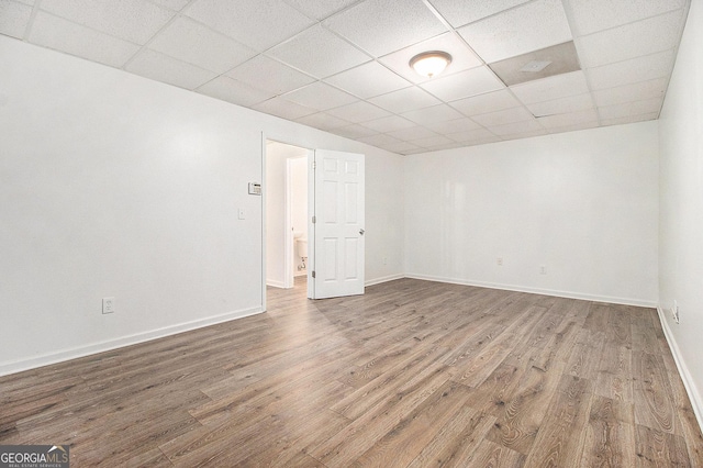 empty room with a paneled ceiling, wood finished floors, and baseboards