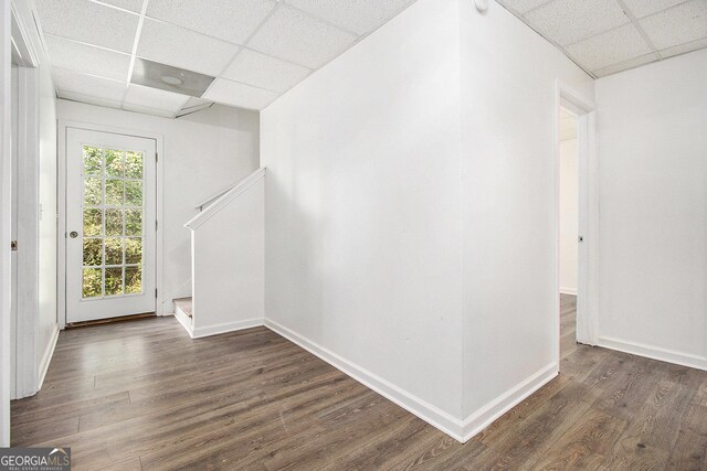 spare room with a drop ceiling, dark wood-type flooring, baseboards, and stairway