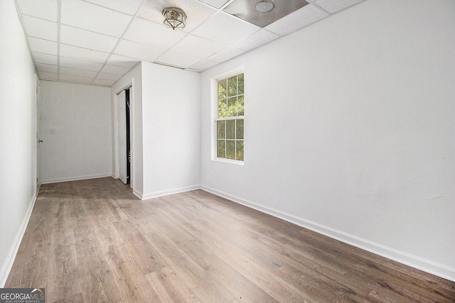 unfurnished room with a drop ceiling, wood finished floors, and baseboards