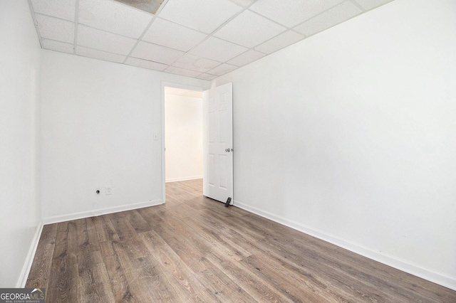 unfurnished room with a drop ceiling, wood finished floors, and baseboards