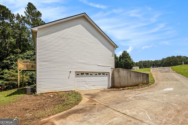 view of side of property featuring a garage, concrete driveway, and cooling unit