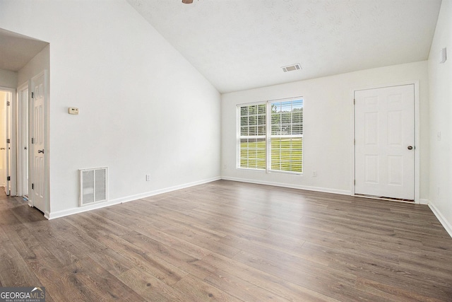 spare room featuring vaulted ceiling, wood finished floors, and baseboards
