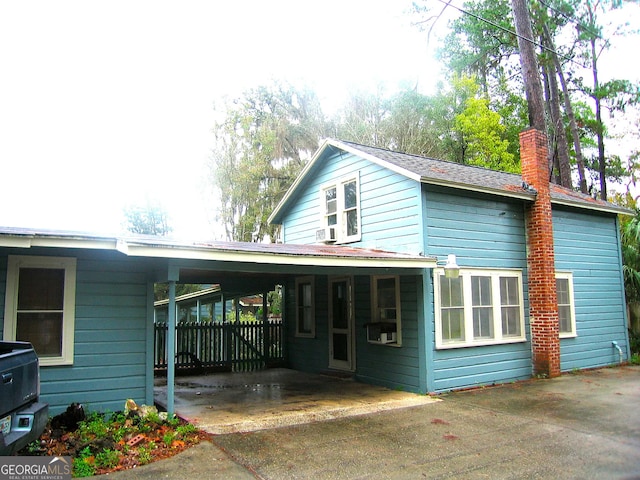 view of front of house with a carport, a chimney, and concrete driveway