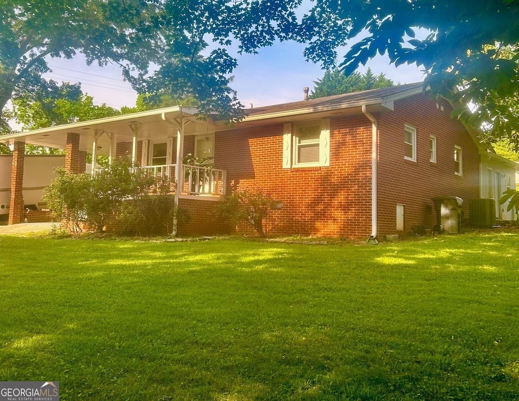 back of house featuring a yard, covered porch, and brick siding