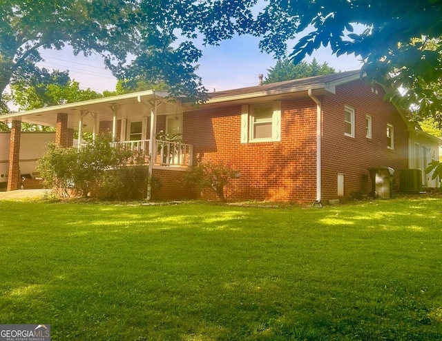 back of house featuring a yard, covered porch, and brick siding