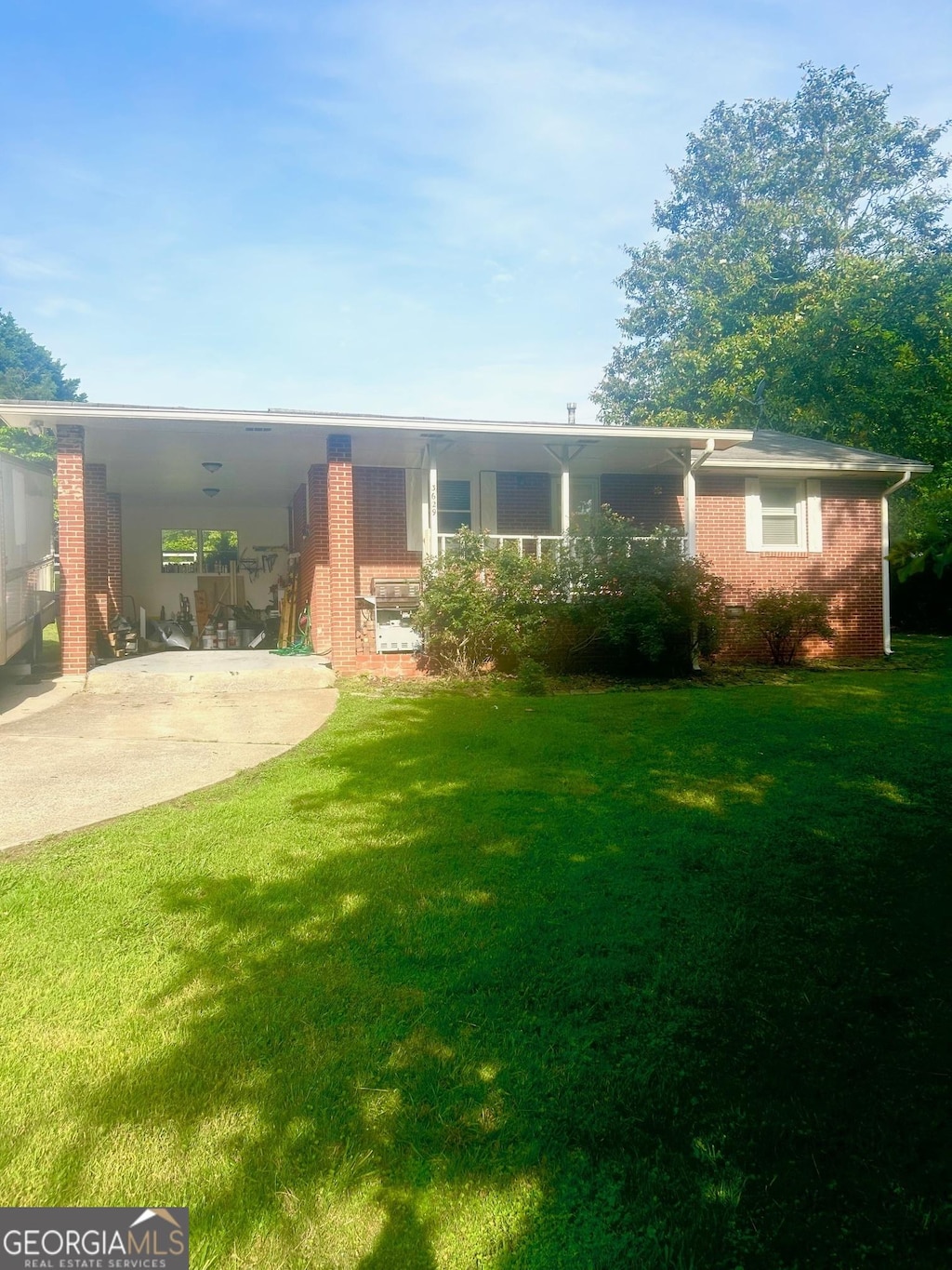 view of front of home featuring concrete driveway, a front lawn, brick siding, and a carport