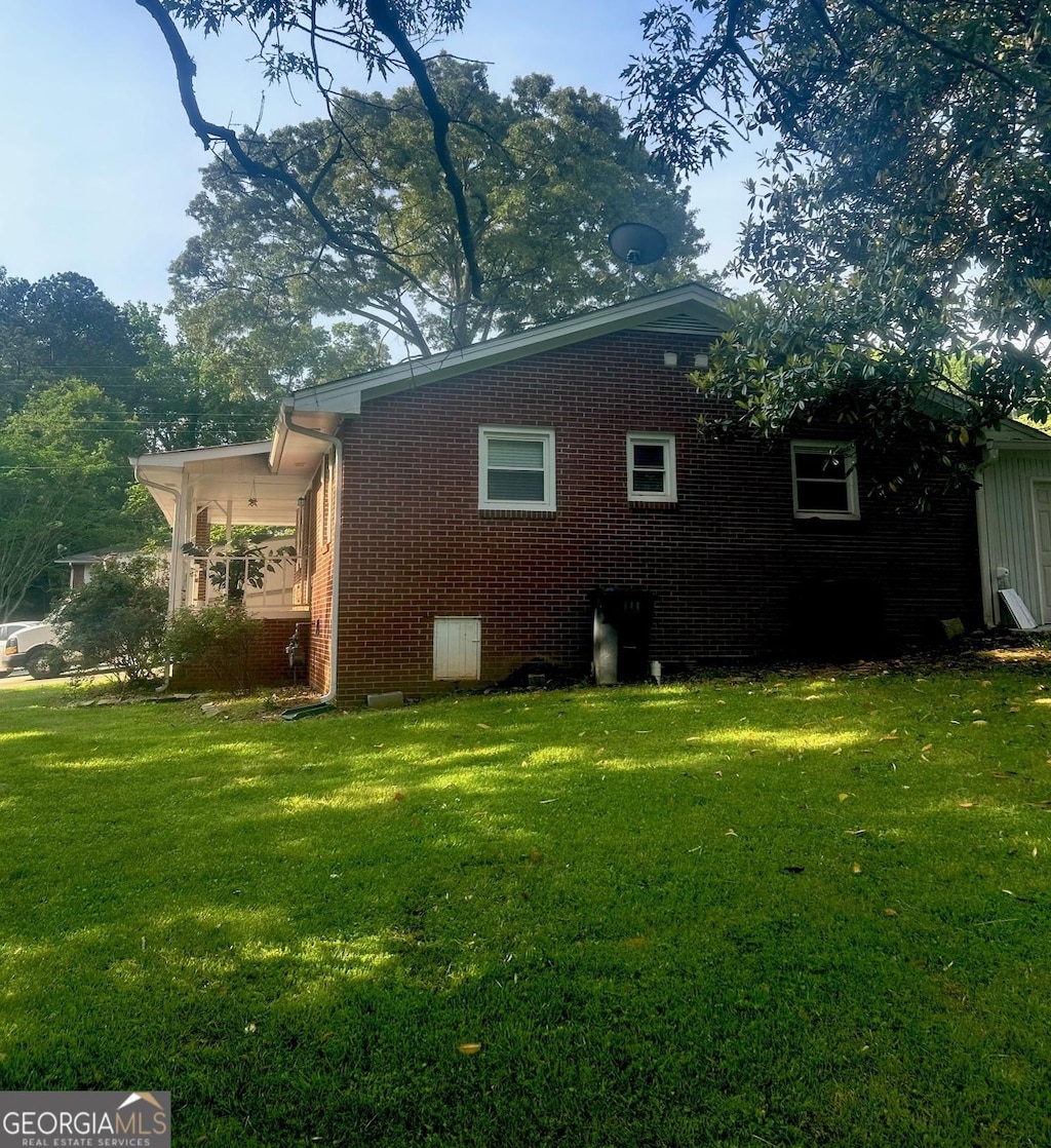 back of house with a lawn and brick siding