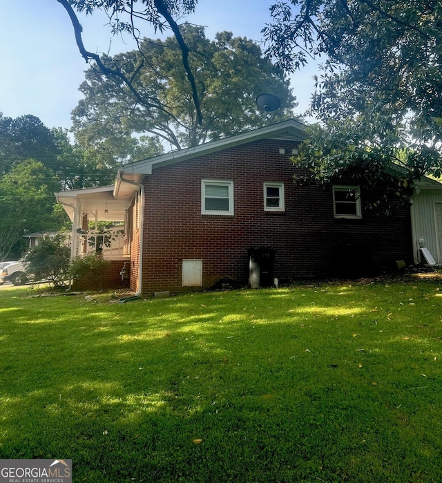 back of house with a lawn and brick siding