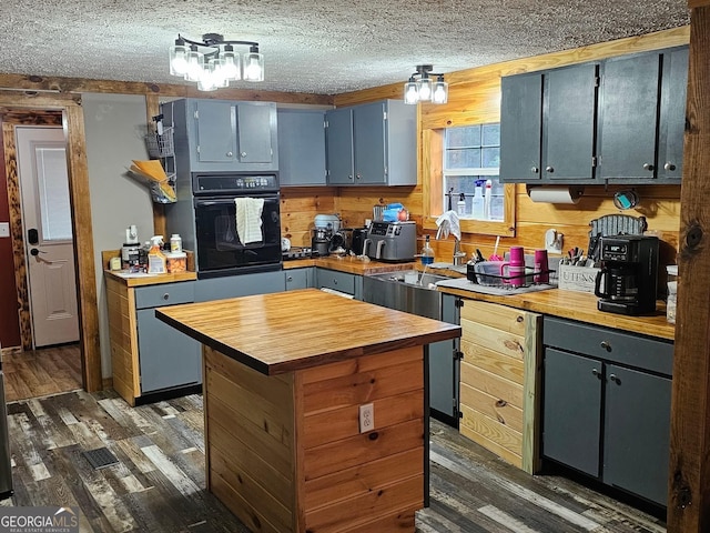 536 Gov Seay Rd, Collins, GA 30421 - kitchen with black oven, wooden counters, dark wood-style floors, a center island, and a textured ceiling