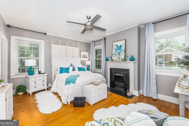 1101 Cherokee Dr, Waycross, GA 31501 - bedroom featuring a fireplace with flush hearth, baseboards, light wood-style floors, a ceiling fan, and ornamental molding