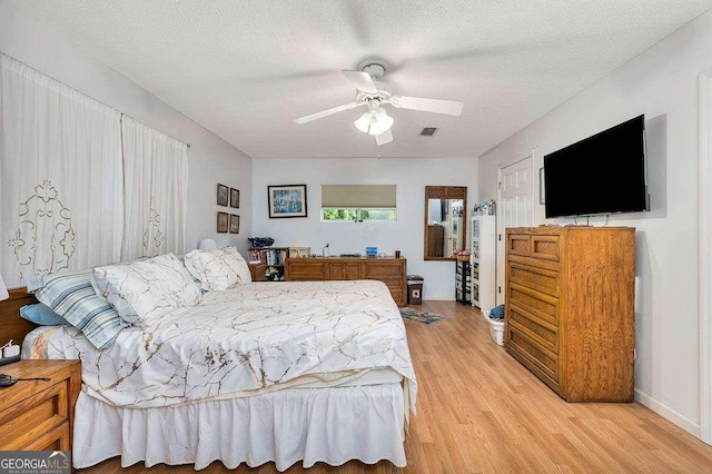 503 Marsh Cir, Saint Simons, GA 31522 - bedroom featuring light wood-style floors, a textured ceiling, ceiling fan, and baseboards