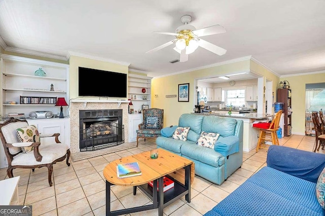 503 Marsh Cir, Saint Simons, GA 31522 - living room featuring light tile patterned floors, crown molding, ceiling fan, a fireplace, and built in features