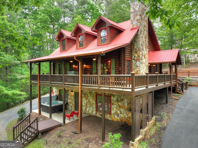 log-style house featuring a hot tub, stone siding, and a deck