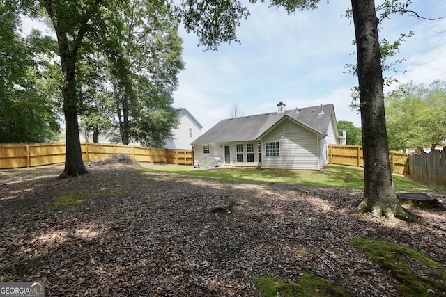 rear view of house with a fenced backyard and metal roof