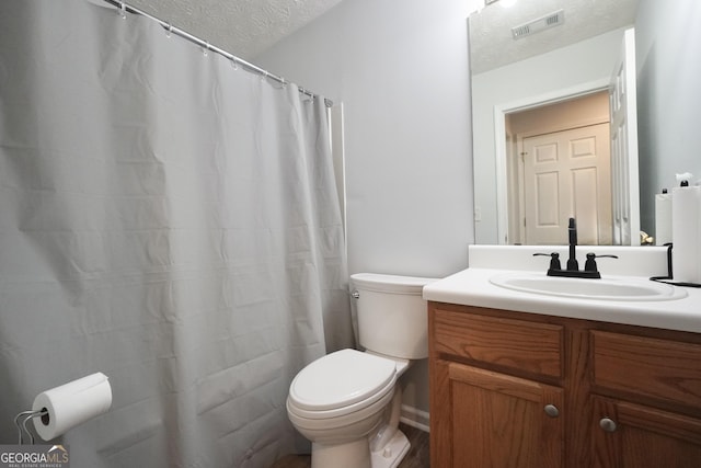 bathroom with a textured ceiling, toilet, and vanity